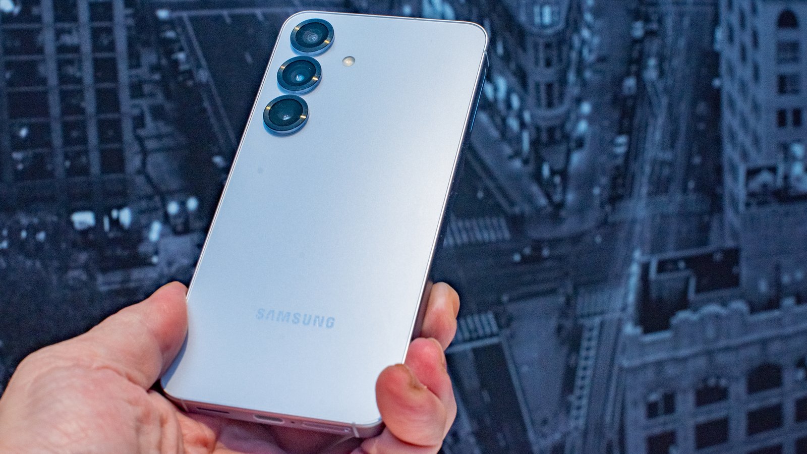تمسك Samsung Galaxy S25 في متناول اليد بزاوية لتعكس شعار Samsung