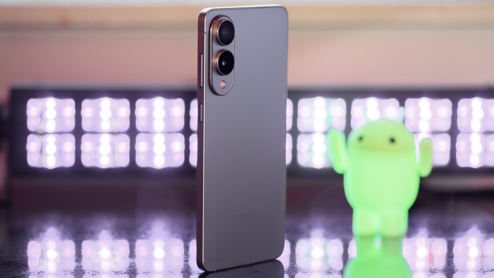 Samsung Galaxy S25 Edge from a 3/4 angle with black lights and an Android figuring blurred in the background