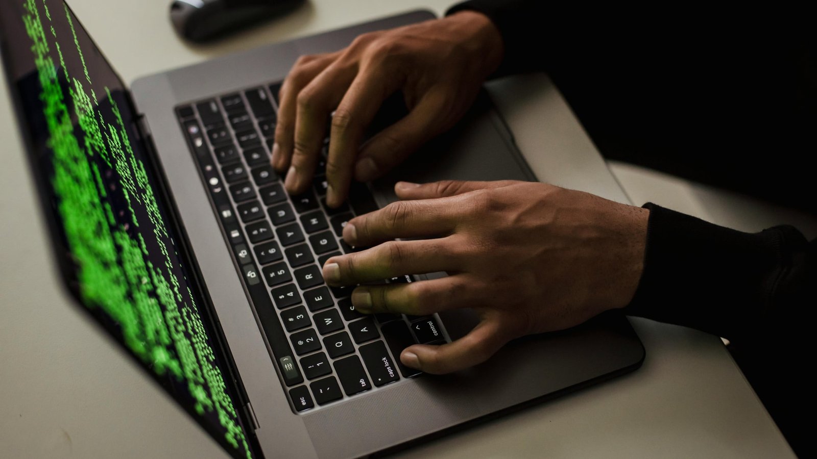 كتب هاكر على جهاز كمبيوتر محمول MacBook مع رمز على الشاشة.